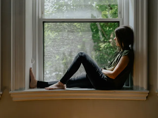 A woman sitting on a window sill, thinking